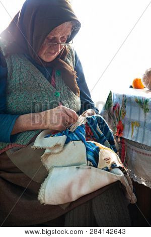 Muntele Bocului, Romania - February 7, 2019: Old rural woman called Lele Maria and her beautiful handworks. Romanian rural environment.