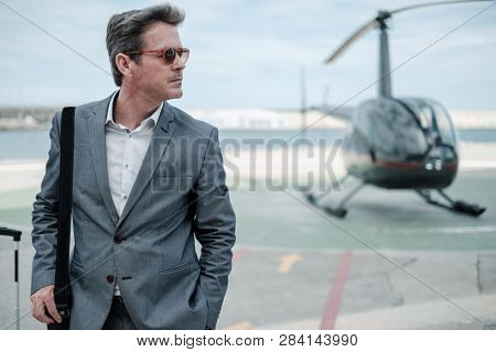 Businessman talking on cellphone near private helicopter