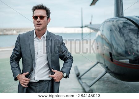 Businessman talking on cellphone near private helicopter