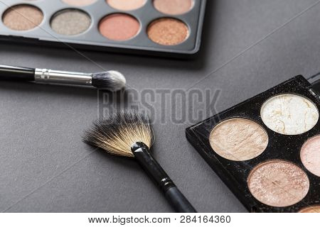 High Angle View Of An Eyeshadow Palette, Highlighter Palette, Highlighter Make Up Brush And An Eyeli