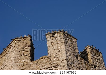 The Top Part Of The Tower In The Visby City Wall Witrh Its Parapet Against A Blue Sky.