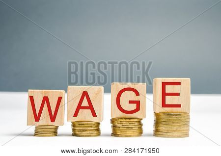 Wooden Blocks With Coins And The Word Wage. Increase Of Salary. Wage Rates. Career Growth. Increase 