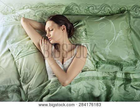 Beautiful young woman sleeping in luxury bed. Bed is made with linen embroidered percale.