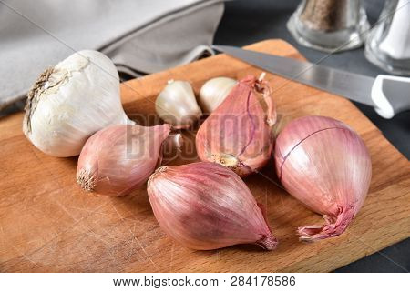 Fresh Organic Shallots And Garlic On A Cutting Board