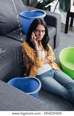 Uspet Woman With Smartphone Looking At Water Drops In Living Room