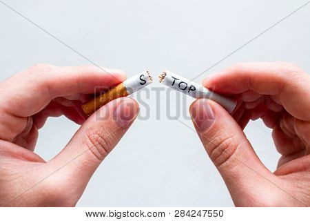 Smoker Breaks A Cigarette With The Word Stop. Concept Stop Smoking On White Background