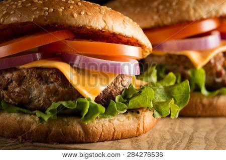 Home Made Hamburger With Beef, Onion, Tomato, Lettuce And Cheese. Fresh Burger Close Up On Wooden Ru