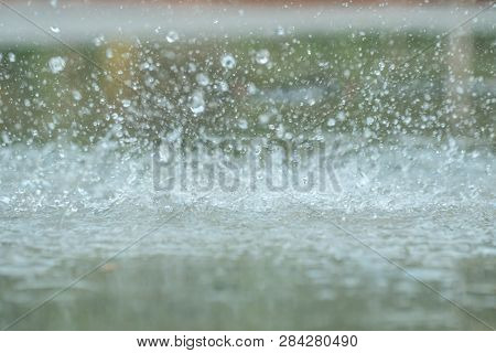 Rain Drops Falling In A Big Puddle On Urban Asphalt In The Town. Raindrops Close-up, Bad Weather In