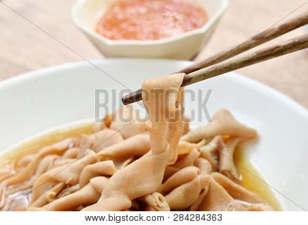 Wooden Chopsticks Picking Stewed Duck Intestine In Brown Soy Soup Dipping Spicy Sauce