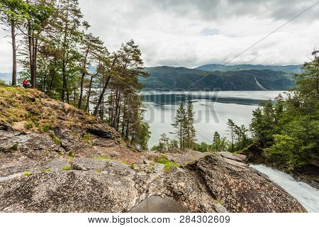 Female Tourist Enjoying Fjord View Ysaudafjord On Overcast Weather, View From Svandalsfossen Waterfa