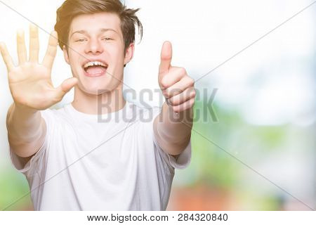 Young handsome man wearing casual white t-shirt over isolated background showing and pointing up with fingers number six while smiling confident and happy.