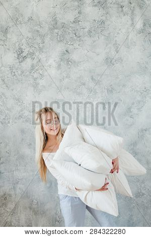 Quality Bedding. Sound Sleep Concept. Smiling Woman Hold Pile Of Pillows. Copy Space On Grey Texture