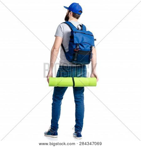 A Man Tourist In Jeans And Cap, Blue Backpack Karemat Standing Looking On White Background Isolation