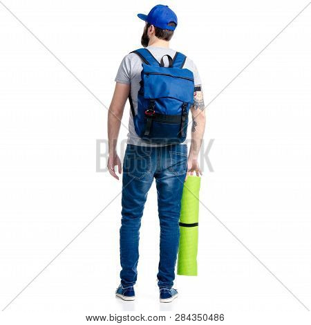 A Man Tourist In Jeans And Cap, Blue Backpack Karemat Standing Looking On White Background Isolation