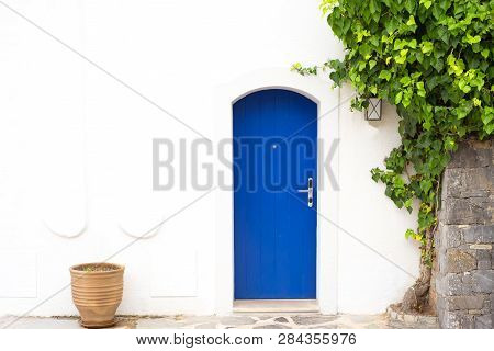 Traditional Greek Blue Door With White Wall, Plant And Terra Cota Vase