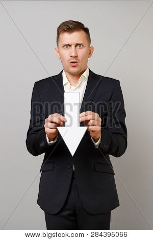 Shocked Concerned Young Business Man In Classic Black Suit, Shirt Holding Down Value Fall Arrow Isol