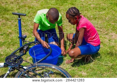 African Children Fixing A Puncture On A Bike