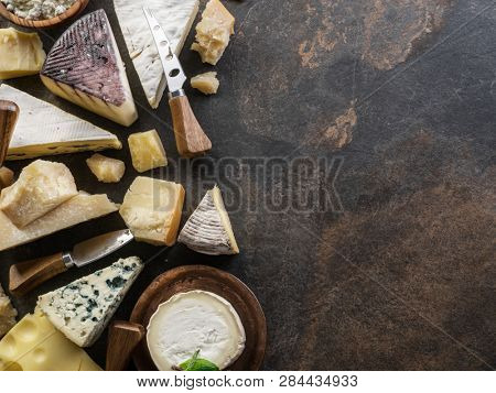 Assortment of organic cheeses on stone background. Top view. Tasty cheese starter.