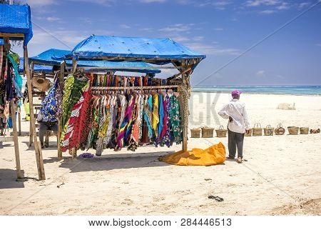 Diani Beach, Kenya - October 10, 2018: Native African Man And Typical Wooden Stall With Colorful Fab