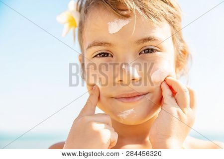 Child On The Beach Smears Sunscreen. Selective Focus.
