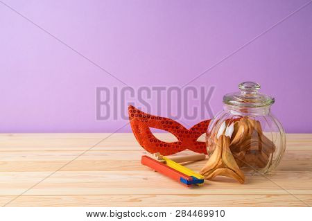 Jewish Holiday Purim Background With Glass Jar, Carnival Mask, Noisemaker And Hamantaschen Cookies O