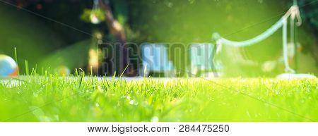 Selective Focus On Green Grass With Water Drops As Dew And Bokeh Background On The House Yard With S