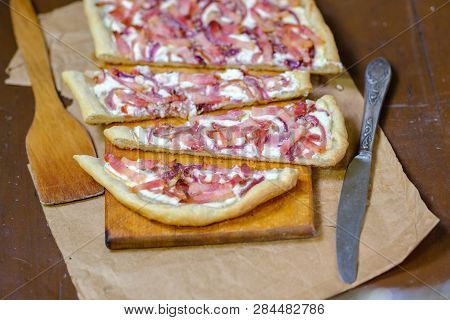 Alsatian Tart Flambé Or Flammkuchen With Bacon And Onions On A Dark Table.