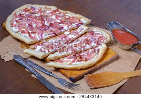 Alsatian Tart Flambé Or Flammkuchen With Bacon And Onions On A Dark Table.