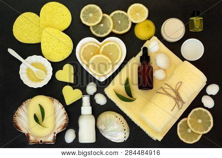 Lemon spa beauty skin care and body care treatment products including  lemons, almond oil, natural soaps, moisturiser, lotion and aromatherapy essential oil. Top view on slate.