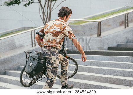 Moscow, Russin Federation - July 28, 2017: Side View Of A Camouflaged Male Cyclist With Bicycle Unde