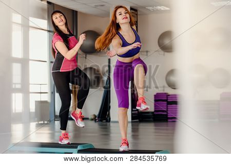 Athletic Mother And Daughter Raising Legs On Step Platforms