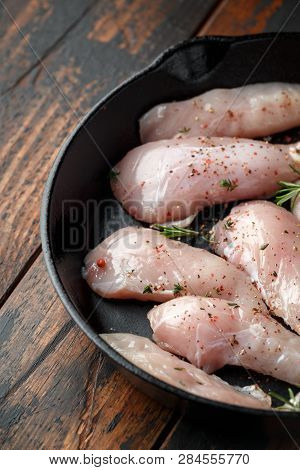 Raw Chicken Breast Mini Fillets In Rastic Cast Iron Skillet, Frying Pan With Herbs And Sea Salt