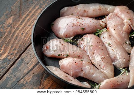 Raw Chicken Breast Mini Fillets In Rastic Cast Iron Skillet, Frying Pan With Herbs And Sea Salt