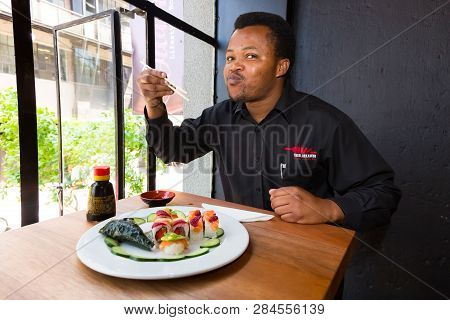 African Man Eating Sushi In A Restaurant