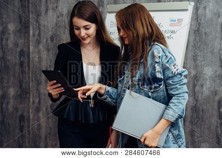 Two Young Women Looking At Screen Of Tablet Pc.