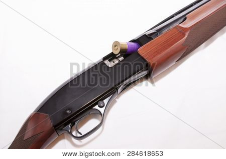 A Purple 12 Gauge Shotgun Shell Shown Partially In The Chamber Of A 12 Gauge Shotgun On A White Back