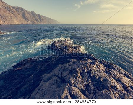Waves Splashing Into Volcanic Coast At Sunset.