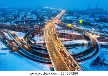 Aerial View Of The Road In Modern City At Night In Fog. Top View Of Traffic In Highway. Winter Citys