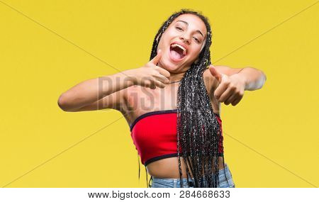 Young braided hair african american with pigmentation blemish birth mark over isolated background approving doing positive gesture with hand, thumbs up smiling and happy for success. Looking