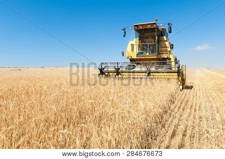 Agricultural Machinery Working On The Barley Tour With Sunny Day