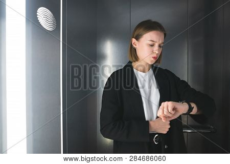Anxious Woman It The Elevator Is Being Late. Businesswoman Is Looking At Her Watch Checking Time. Em