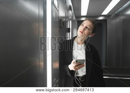 Ambitious Employee Is Waiting The Elevator To Stop And Listening To Music In Her Headphones Using Sm
