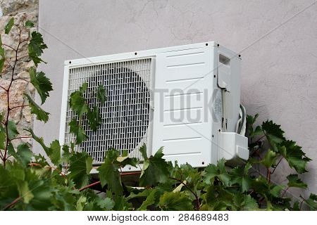 Wall Mounted Outside Air Conditioner Ac Unit Mounted On Cracked Back Wall With Stone Tiles Part Of F