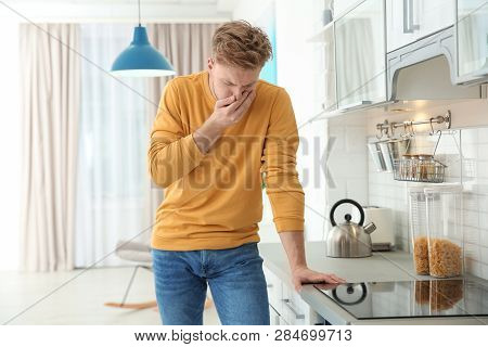 Young Man Having Nausea In Kitchen. Feeling Sick
