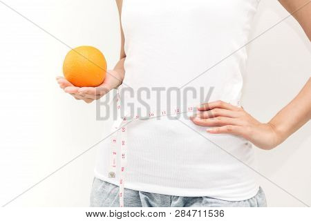 Woman Holding Orange And Measuring Her Waist By Measure Tape