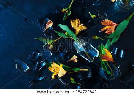 Broken Glass Vase With Yellow Flowers. Spring Floral Concept With Alstroemeria On A Black Background