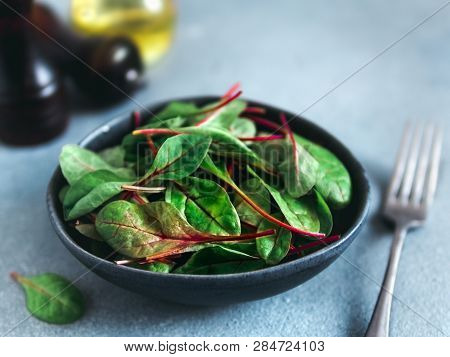 Fresh Salad Of Green Chard Leaves Or Mangold On Gray Stone Background. Fresh Baby Beet Leaves In Cra