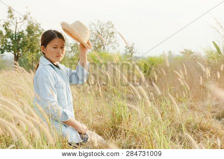 Girl Wearing A Hat Sitting Looking At Desho Grass.