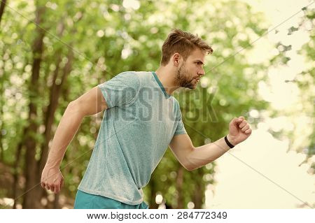 Moving To His Goal. Man Confident Young Running In Park, Side View. Sportsman Ambitiously Moves To A
