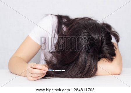 The Girl Cries At The Table And Holds In Her Hand A Test For Pregnancy Is Negative, Infertility, Fer
